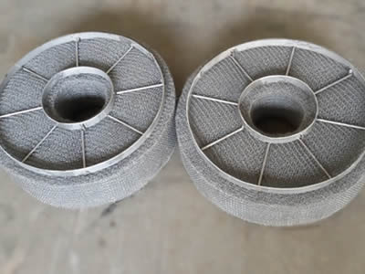 Zwei ringförmige Demister-Pads mit Rundstab und flachem Streifen-Trag gitter auf dem Boden.